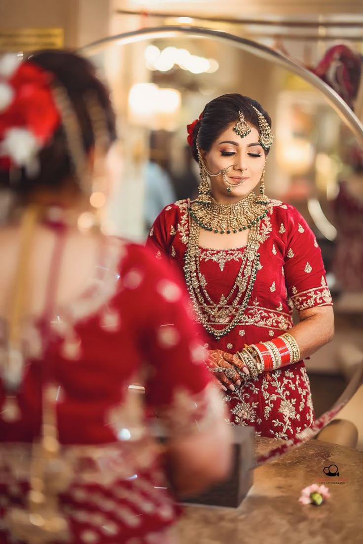 a woman in a red dress is looking at herself in the mirror while another person looks on