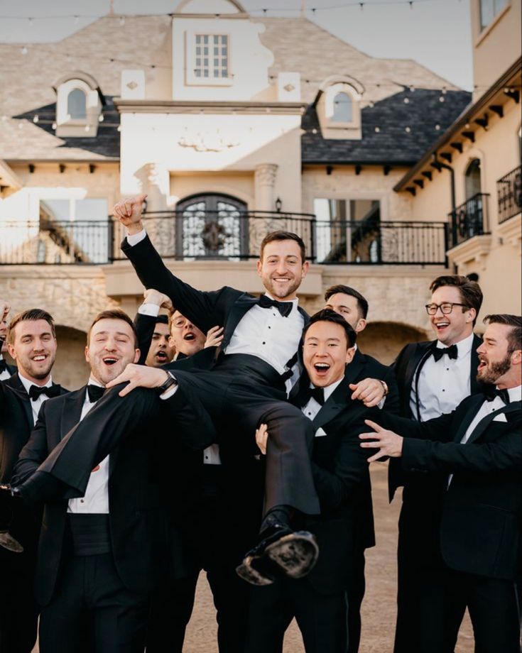 a group of men in tuxedos are posing for a photo with each other