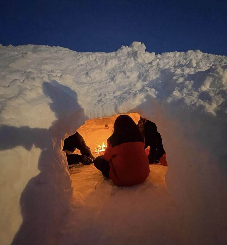 two people sitting in the middle of a snow covered area with a bright light shining on them