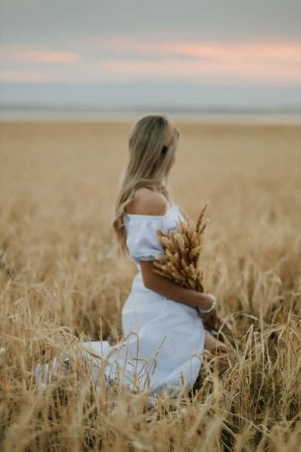 a woman in a white dress standing in a wheat field