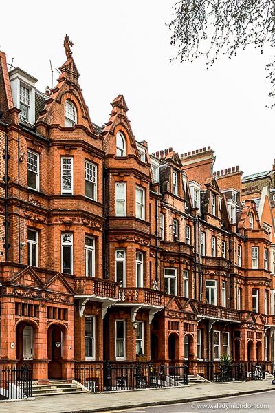 a row of red brick buildings next to each other on a city street in front of a tree