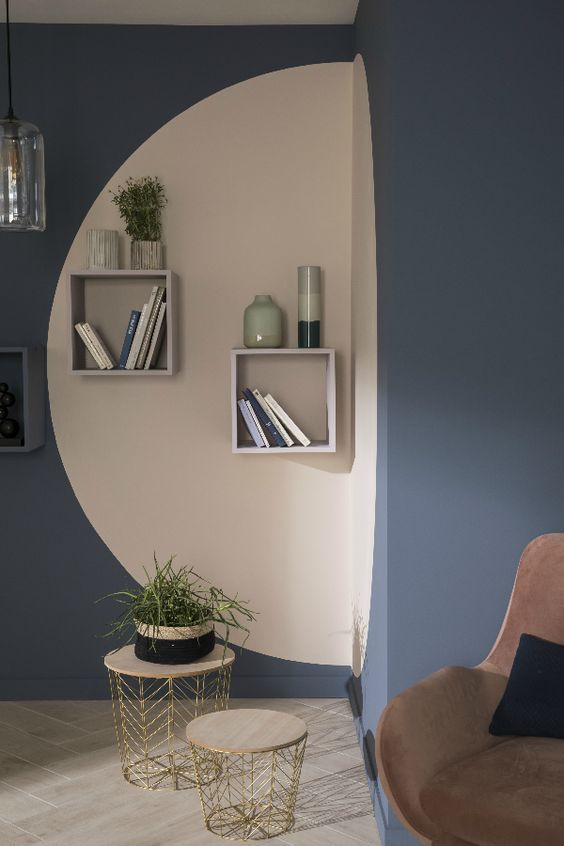 a living room with blue walls and shelves on the wall next to a planter