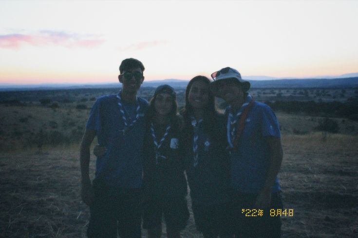 three people are standing in the grass at sunset