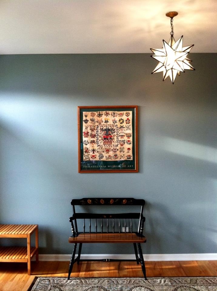 a room with blue walls and a wooden bench in the corner next to a rug