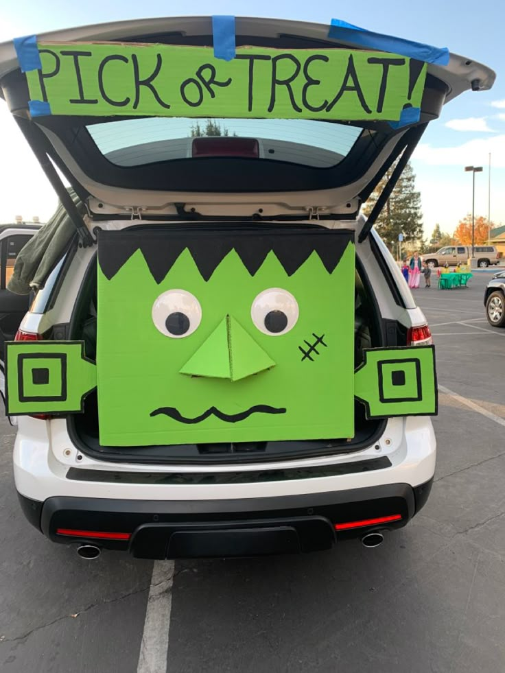 the back of a car with a paper cut out of it's face and word pick or treat written on its trunk