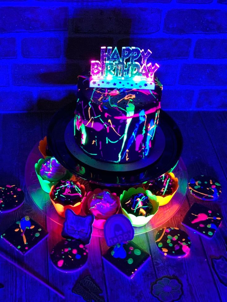 a birthday cake is lit up with neon lights