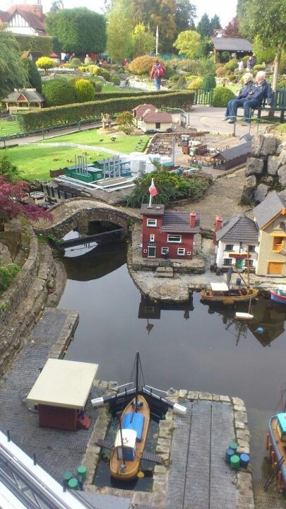 there are many small boats on the water in this miniature town park, and people can see them from above