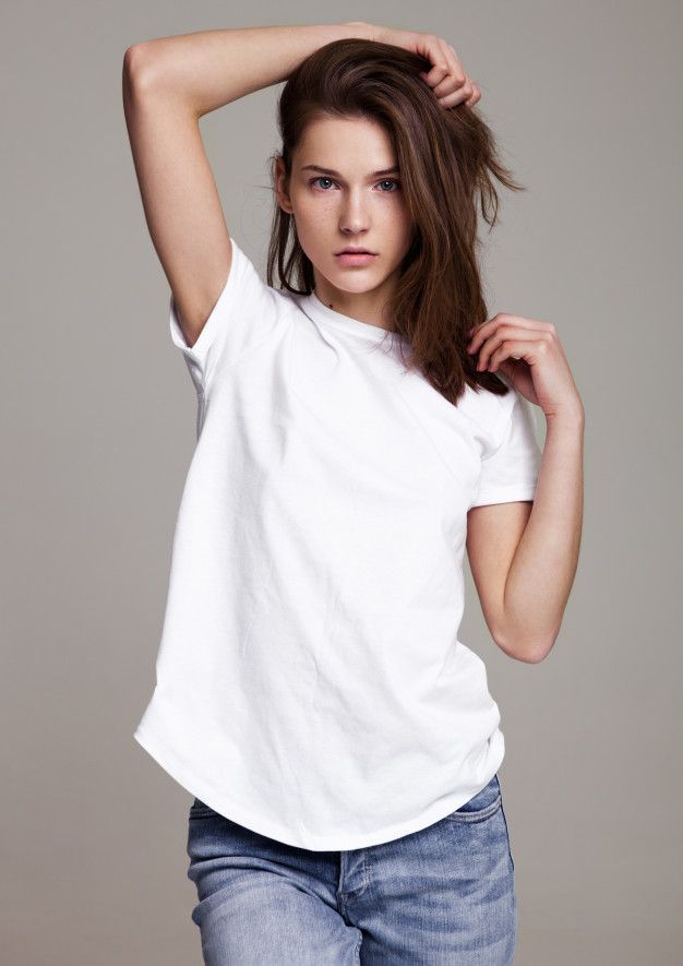 a woman in white shirt and jeans holding her hair