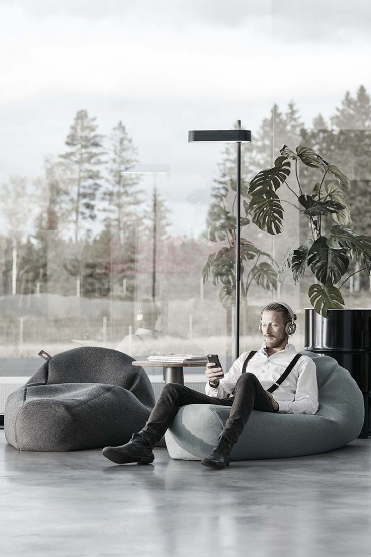 a man sitting on a bean bag chair with a drink in his hand and looking at the camera