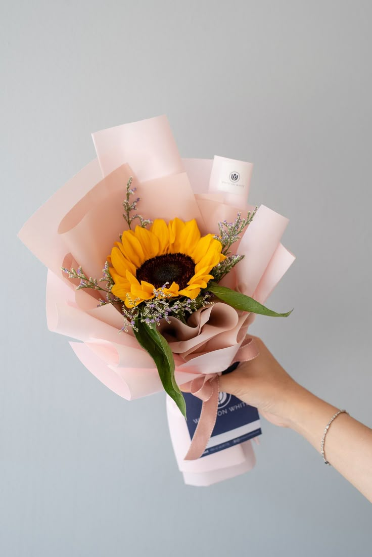 a person holding a bouquet of flowers in their hand with the sunflower on top