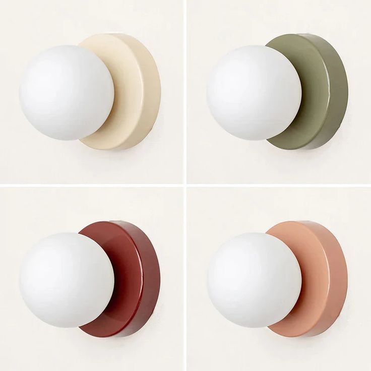 four different colored knobs on the side of a white wall and one has an egg in it