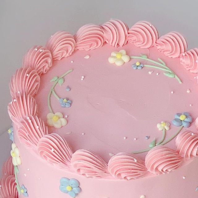 a pink frosted cake with flowers on it