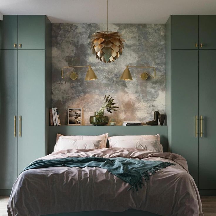 a bed sitting in a bedroom next to green cupboards and a wall mounted light