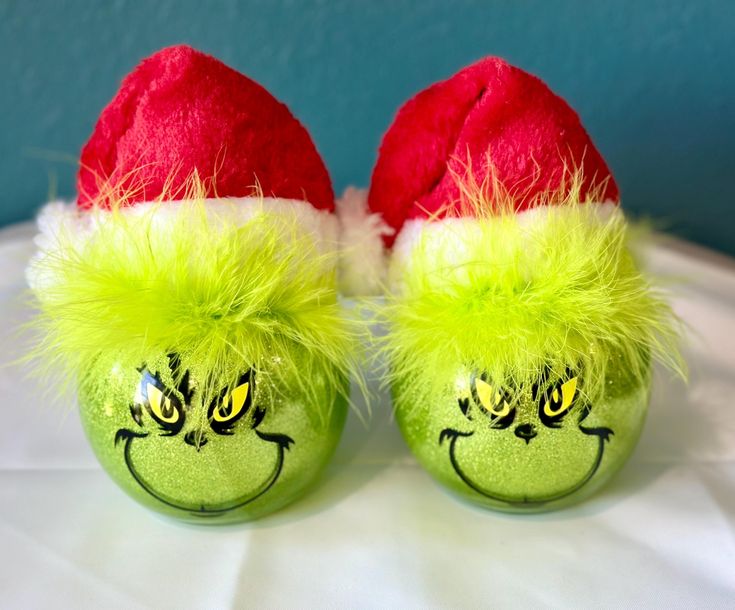 two green balls with yellow and red hair on them, one has a grin face painted on it