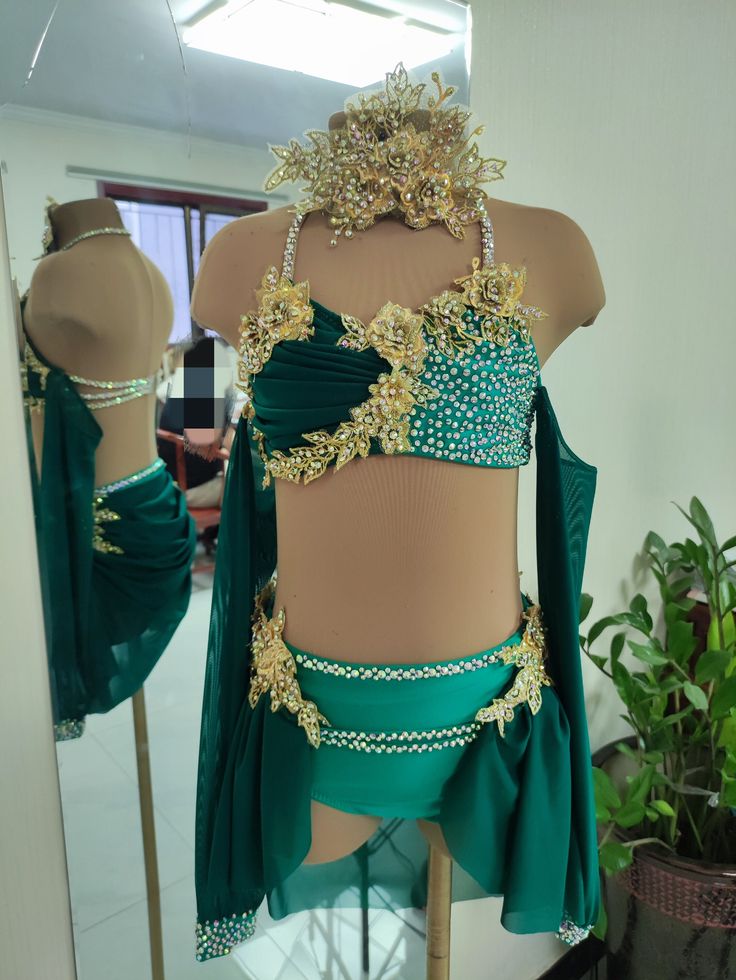 a mannequin with green and gold clothing on display in front of a mirror