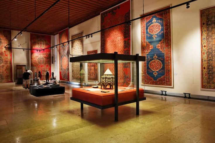 a room filled with lots of different types of rugs on display in glass cases