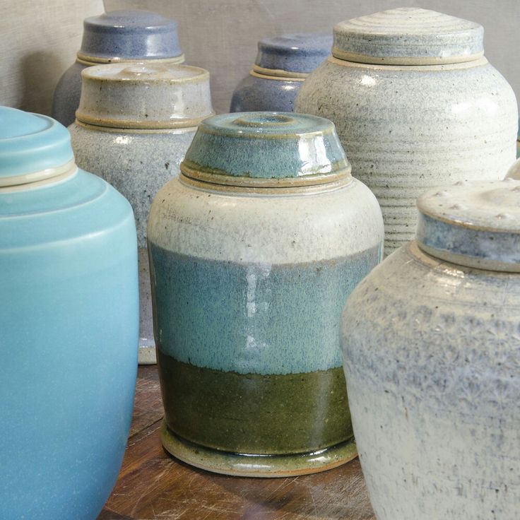 there are many different colored vases on the table together and one is blue, green, white and grey