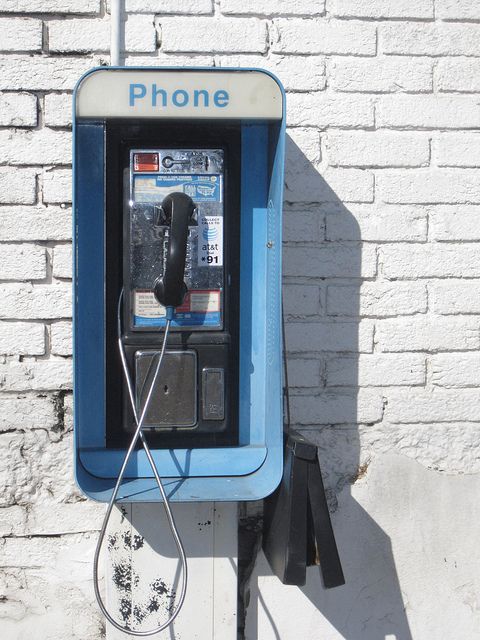 an old fashioned pay phone sitting next to a brick wall