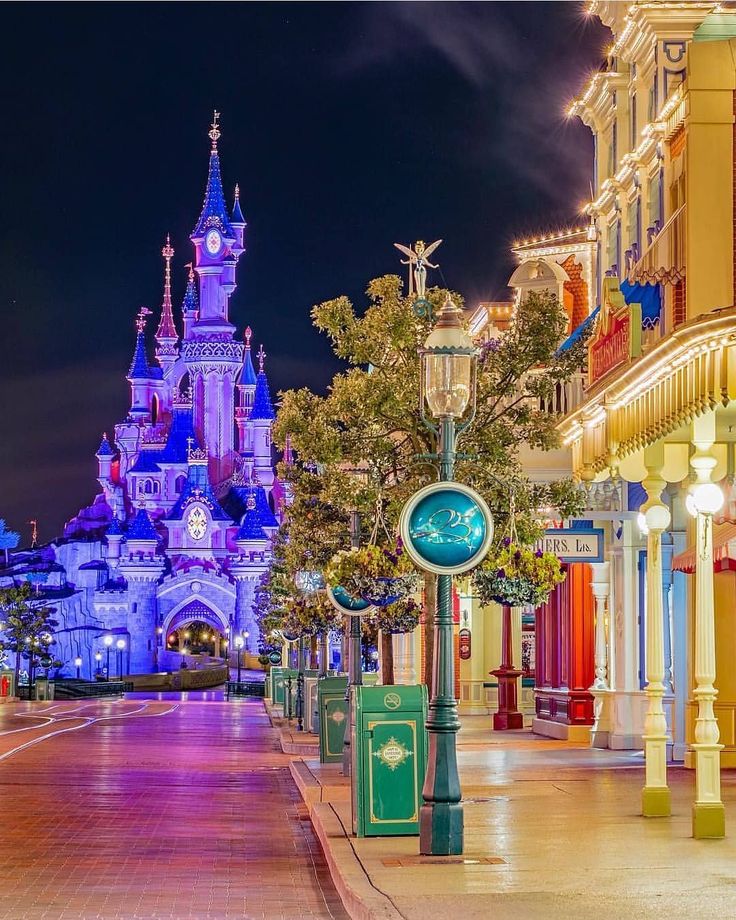 a street scene with focus on the castle and clock tower in the background at night