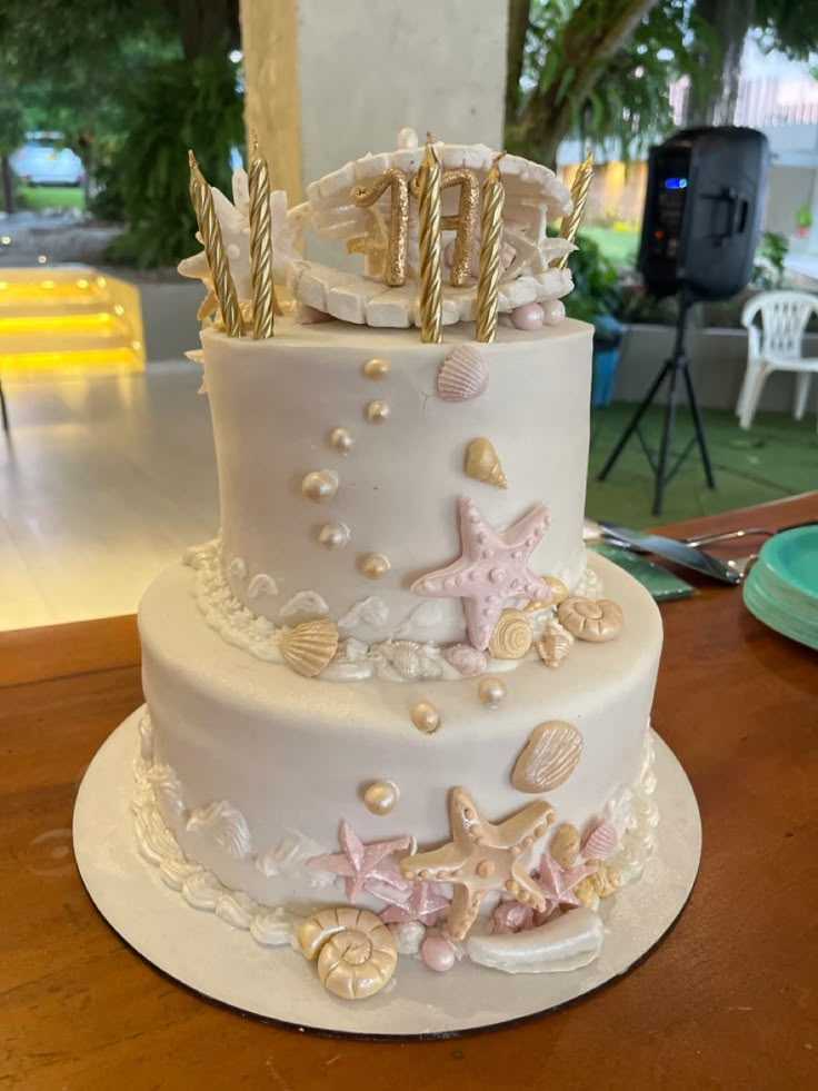 a three tiered wedding cake with seashells and starfish