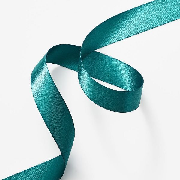 a teal green satin ribbon on a white background with room for text or image