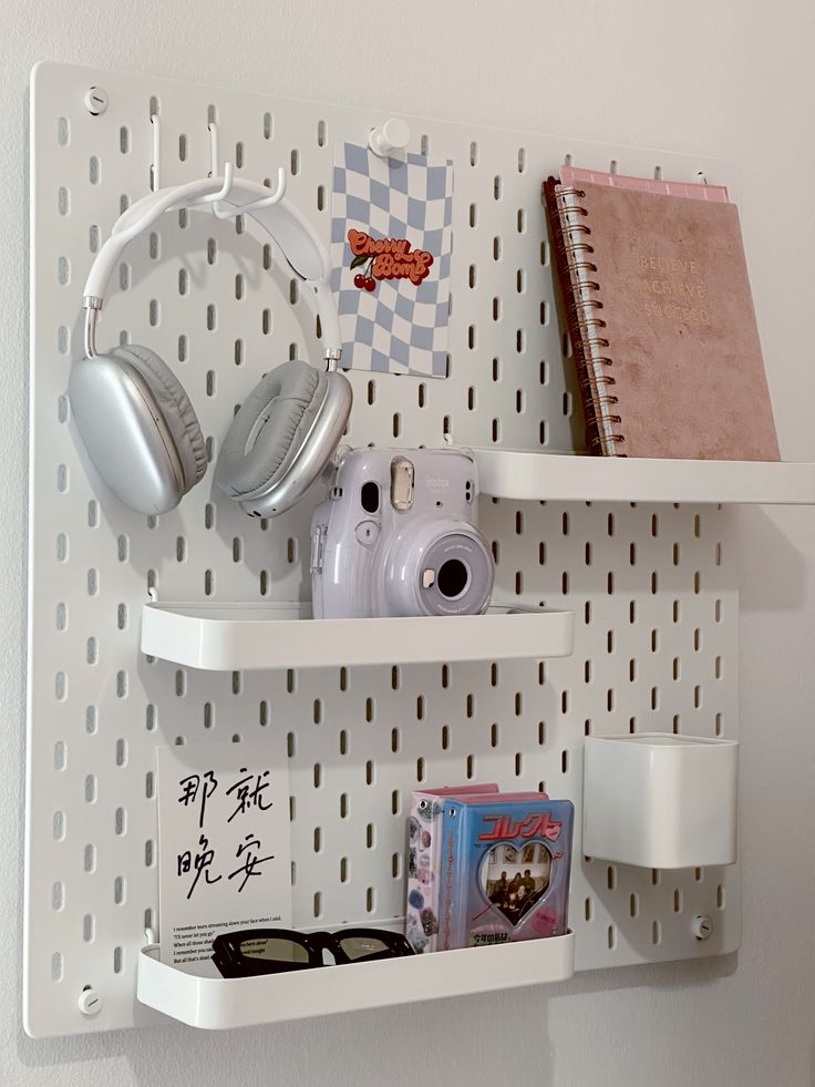 two white shelves with books, headphones and other items on them