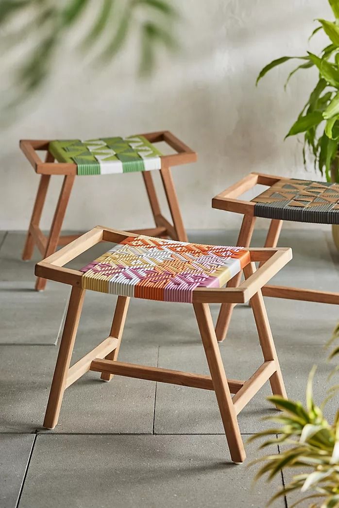 two wooden chairs sitting next to each other on top of a cement floor with plants in the background