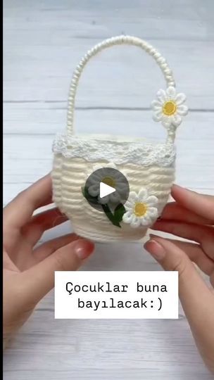 a person holding a small white basket with daisies on the side and text reading coculiar buna bayilacak?