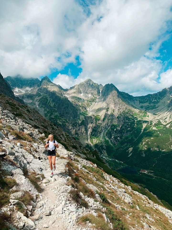 a woman is running on a trail in the mountains