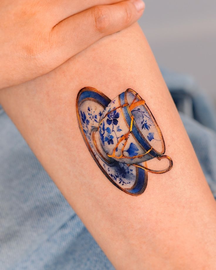 a woman's arm with two coffee cups on it, painted in blue and orange