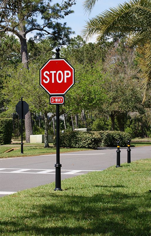 a red stop sign sitting on the side of a road next to a lush green park