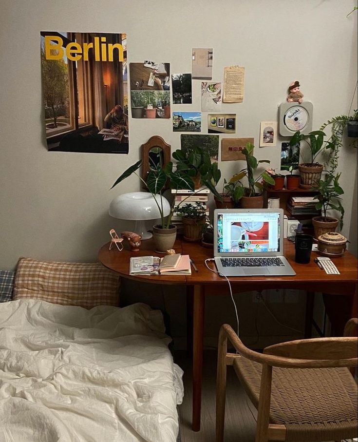 a laptop computer sitting on top of a wooden desk next to a chair and table