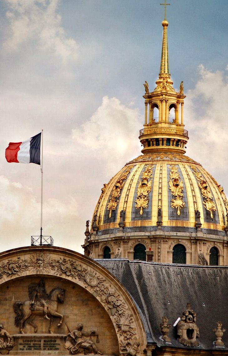 the top of a building with a flag flying in front of it and a gold dome