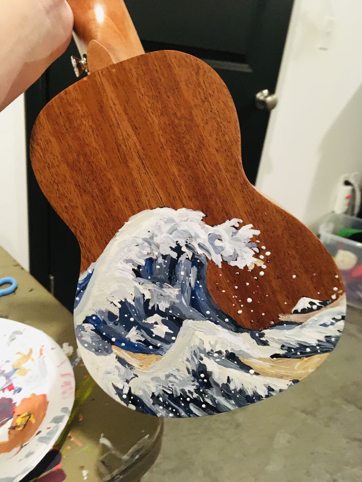 a wooden guitar with an image of the great wave painted on it