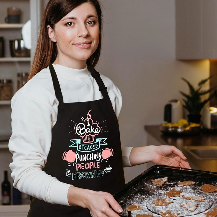 a woman in an apron holding a tray of cookies