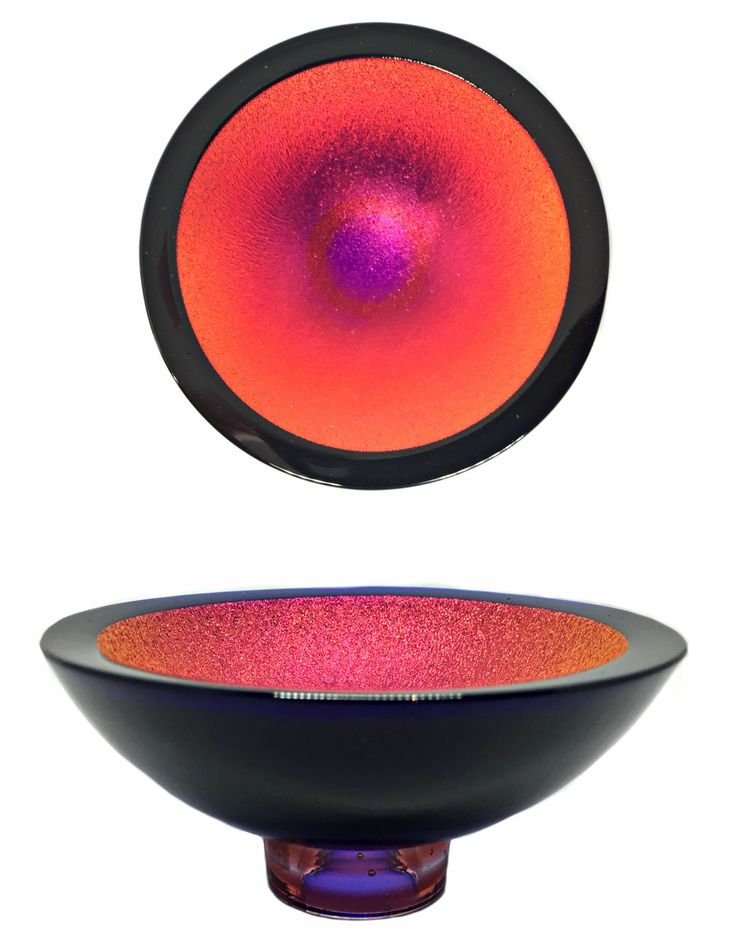 an orange and pink bowl sitting on top of a white table next to a black plate