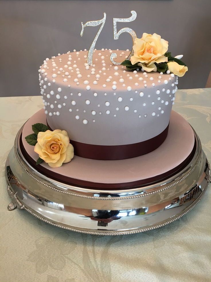 a white and brown cake with polka dots on the top is sitting on a silver platter