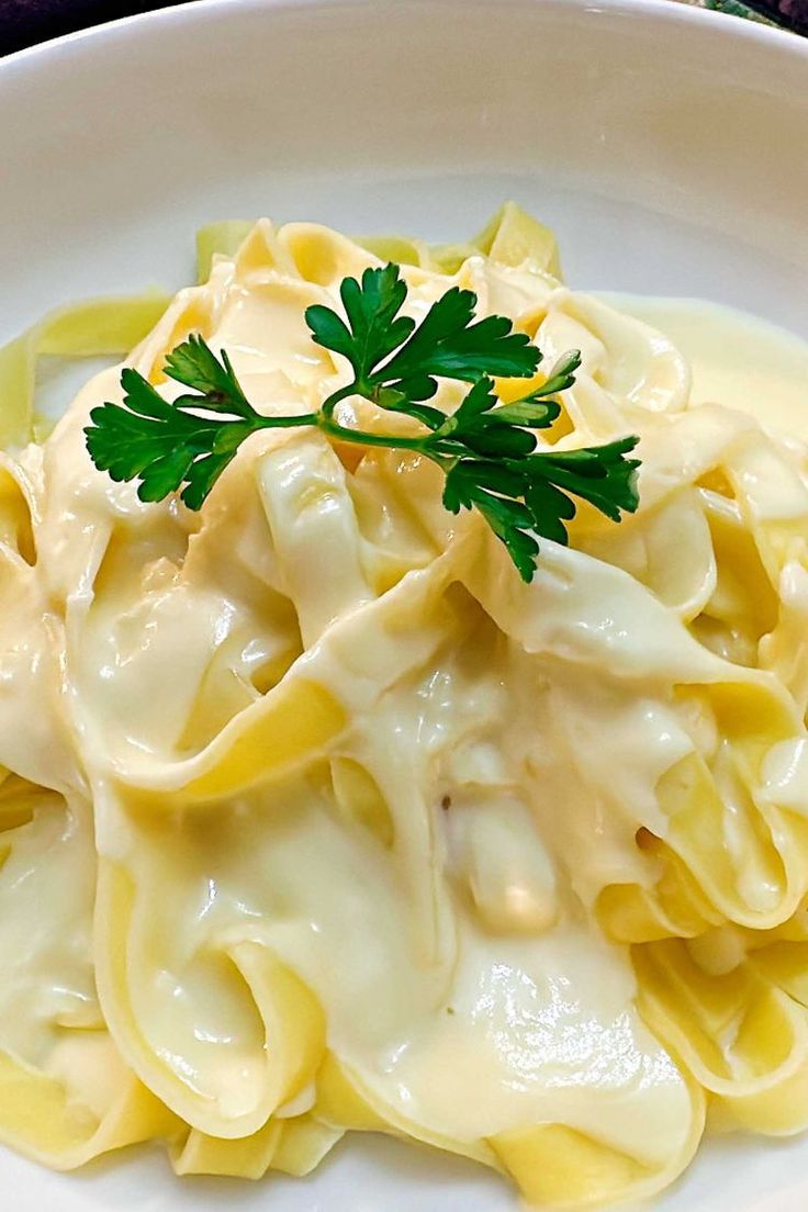 a white plate topped with pasta covered in sauce and parsley