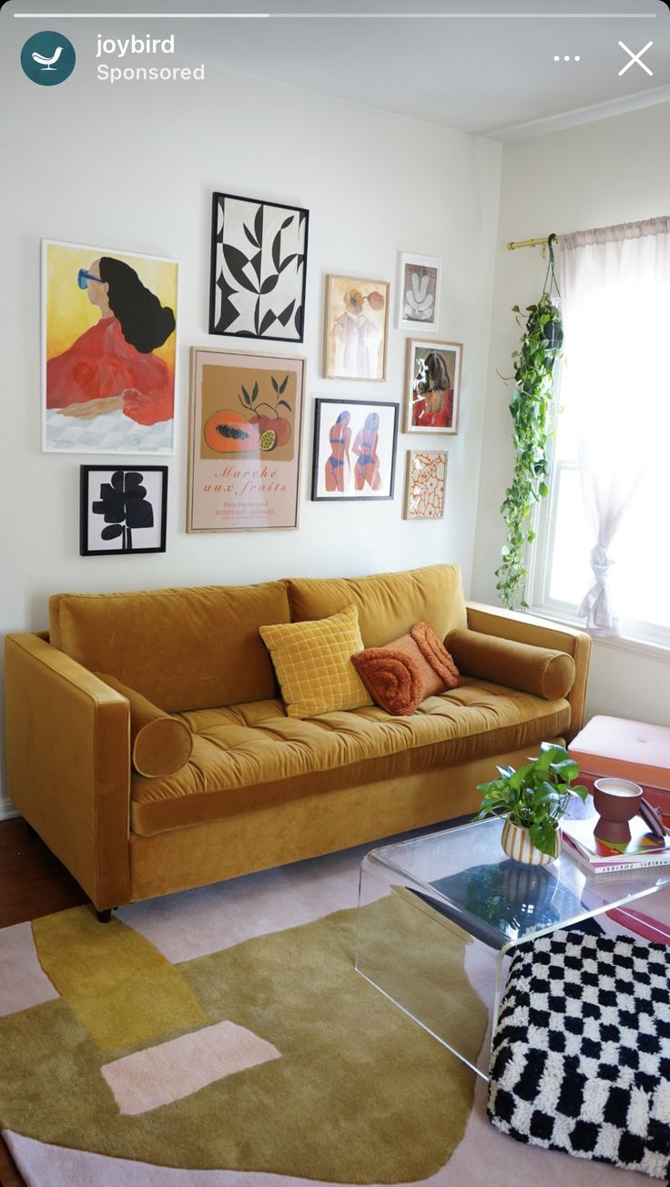 a living room with yellow couches and pictures on the wall above it's glass coffee table