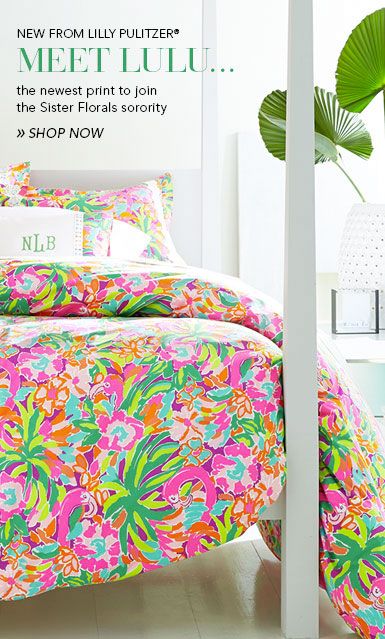 a bed with colorful comforters and pillows in a room next to a potted plant