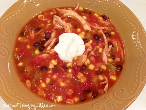 a bowl of soup with corn, chicken and sour cream in it on a plate