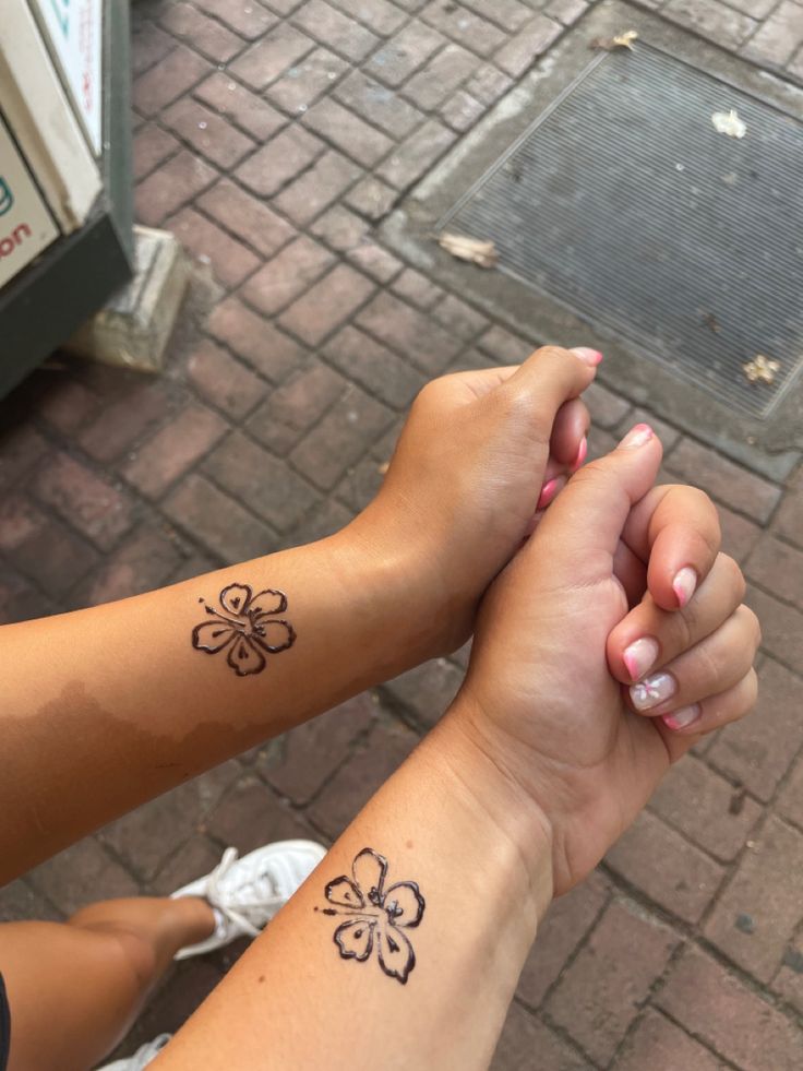 two people holding hands with tattoos on their arms