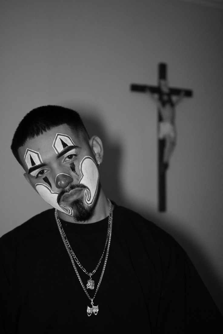 a man with face paint and a cross behind him