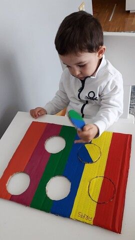 a little boy that is sitting at a table playing with some sort of crafting material