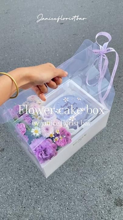 someone is holding a flower cake box in their hand and it's inside the package