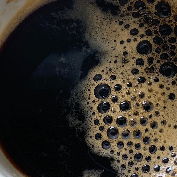 a close up view of some liquid in a white cup with brown and black spots