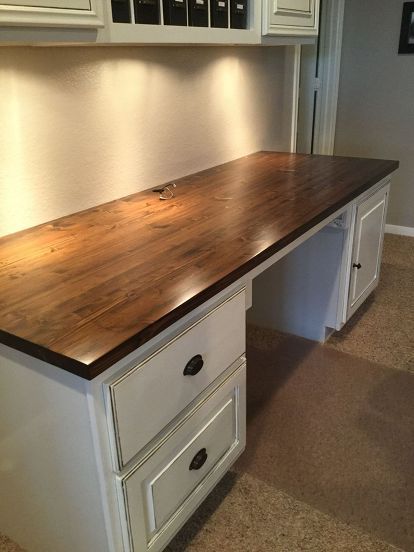 a wooden counter top sitting in the middle of a kitchen next to white cupboards