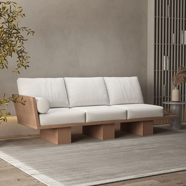 a white couch sitting on top of a wooden floor next to a plant in a living room