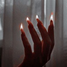 a woman's hand with red nail polish holding out her fingers in front of a window