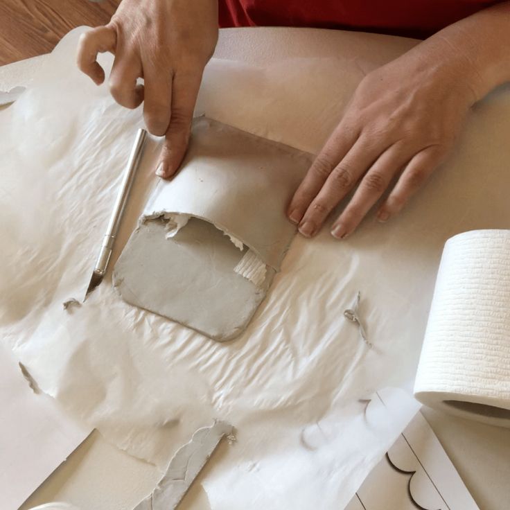 a person is cutting up some paper with scissors and tape on the table next to them